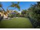 Spacious backyard with a manicured lawn, lush tropical plants, and an inviting patio seating area at 1806 Caribbean Dr, Sarasota, FL 34231