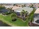 A landscaped backyard with a screened-in patio surrounded by well-maintained grass, tropical plants, and a view of a serene pond at 2183 Nettlebush Ln, Venice, FL 34292