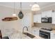Close-up of a kitchen island with a sink, modern faucet, and view of stainless steel appliances and pendant lighting at 2183 Nettlebush Ln, Venice, FL 34292