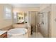 A spa-like bathroom has a tub, and glass shower, with nice tiling at 2183 Nettlebush Ln, Venice, FL 34292