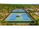 Aerial view of well-maintained community tennis courts surrounded by lush greenery, offering a recreational amenity at 2183 Nettlebush Ln, Venice, FL 34292