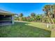 Spacious backyard featuring lush green grass, tropical foliage, and a screened patio at 313 Overbrook St, Port Charlotte, FL 33954