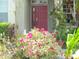 Charming front entrance with a red door surrounded by vibrant flowers and lush tropical landscaping at 315 Londonderry Dr, Sarasota, FL 34240