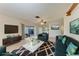 Staged living room with couches, rug, TV, and view through sliding glass doors to the lanai and community landscape at 3259 Fairhaven Ln # 211, Sarasota, FL 34239