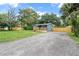 Inviting blue home with wood deck, large gravel driveway and fenced yard surrounded by mature trees at 3561 Elfers Pkwy, New Port Richey, FL 34655