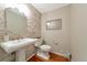 Stylish powder room with a pedestal sink, stacked stone accent wall, and wood floors at 4520 Longspur Ln, Sarasota, FL 34238