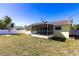 View of the fenced backyard with a lush lawn, landscaping, and the yellow house with screened porch at 4659 Alligator Dr, Venice, FL 34293