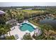 An aerial view of a community pool featuring a jacuzzi, ample lounge chairs, and lush tropical landscaping at 5234 Aqua Breeze Dr, Bradenton, FL 34208