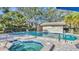 Community pool area with brick pavers, lounge chairs, mature landscaping, and a hot tub at 5655 Pipers Waite # 27, Sarasota, FL 34235