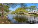 Scenic view of homes bordering a tranquil pond, enhanced by lush trees and a serene blue sky at 5655 Pipers Waite # 27, Sarasota, FL 34235