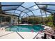 Covered pool with lounge chairs, tropical landscaping, and a palm tree outside the enclosure at 5747 29Th E St, Bradenton, FL 34203