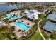 Aerial view of a community pool featuring multiple pools, a water slide, tennis courts, and lush landscaping at 6136 Voyagers Pl, Apollo Beach, FL 33572