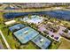 Aerial view of community amenities with multiple tennis courts, swimming pools, and a clubhouse overlooking a scenic pond at 6136 Voyagers Pl, Apollo Beach, FL 33572