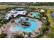 Aerial view of a community pool featuring a waterslide, lounge chairs, and recreational amenities amidst lush landscaping at 6136 Voyagers Pl, Apollo Beach, FL 33572