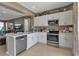 Open kitchen with white cabinets, stainless steel appliances, flowing to an adjacent living area at 6265 Fairmont Ln, Palmetto, FL 34221