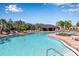 A crystal-clear pool features a covered pavilion, sun loungers, and palm trees for ultimate community relaxation and fun at 6265 Fairmont Ln, Palmetto, FL 34221