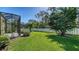 Spacious backyard features a well-manicured lawn, privacy fence, and tropical trees for a serene outdoor space at 7424 Ridgelake Cir, Bradenton, FL 34203