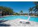 Beautiful community pool area with ample seating, blue water, and tropical palm trees against a clear blue sky at 7424 Ridgelake Cir, Bradenton, FL 34203