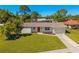 Well-maintained single-story home featuring a red front door, manicured landscaping, and attached garage at 7460 Mariana Dr, Sarasota, FL 34231