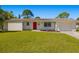 Well-maintained single-story home featuring a red front door, manicured landscaping, and attached garage at 7460 Mariana Dr, Sarasota, FL 34231