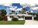 Charming single-story home featuring a well-manicured lawn, red hibiscus, and an attached two-car garage at 800 Everest Rd, Venice, FL 34293
