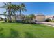 Well-maintained home exterior with a lush green lawn, mature landscaping, and a brick driveway leading to a three-car garage at 8861 17Th Avenue Nw Cir, Bradenton, FL 34209