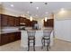 Well-lit kitchen features dark wood cabinetry, granite countertops, and a breakfast bar with two bar stools at 8861 17Th Avenue Nw Cir, Bradenton, FL 34209