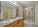 Bathroom features a double sink vanity, large mirror, and glass-enclosed shower at 8996 Excelsior Loop, Venice, FL 34293