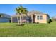 Well-maintained backyard showcasing a covered screened-in patio, complemented by swaying palm trees and lush green grass at 1014 Calico Gln, Bradenton, FL 34212