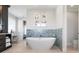 Bright bathroom features a soaking tub, blue mosaic accent wall, and access to a private toilet at 110 10Th S St, Bradenton Beach, FL 34217