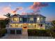 Beautiful two-story home with a red door, a two-car garage and waterfront views at sunset at 110 10Th S St, Bradenton Beach, FL 34217