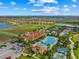 Aerial view of the community with a pool, clubhouse, tennis courts, and lake at 13320 Coluccio St, Venice, FL 34293