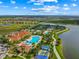 Aerial view of the community featuring a pool, tennis courts, and clubhouse by the lake at 13320 Coluccio St, Venice, FL 34293