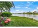 Lush backyard with seating and a view of the tranquil lake and blue skies at 13320 Coluccio St, Venice, FL 34293