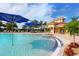 Community pool with blue umbrellas and fountains, surrounded by lush landscaping and comfortable lounge seating at 13320 Coluccio St, Venice, FL 34293