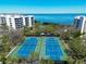 Aerial view of well-maintained tennis courts with ocean views, perfect for recreational activities at 1930 Harbourside Dr # 136, Longboat Key, FL 34228