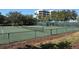 Community tennis courts surrounded by trees with a glimpse of the building in the background at 1930 Harbourside Dr # 136, Longboat Key, FL 34228