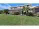 Expansive backyard with lush green lawn, screened in lanai, tropical landscaping, and plenty of space for outdoor enjoyment at 2512 61St E Ave, Ellenton, FL 34222