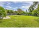 Expansive backyard with lush green grass, bordered by a wooden fence and mature trees at 2566 Tulip St, Sarasota, FL 34239