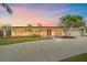 Charming single-story home with a well-manicured lawn, palm trees, and a concrete driveway at sunset at 2905 Bougainvillea St, Sarasota, FL 34239