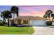 Charming single-story home with a manicured lawn, mature palm trees and a two-car garage with beautiful sunset sky backdrop at 31 Bunker Rd, Rotonda West, FL 33947