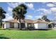 Charming single-story home with a manicured lawn, mature palm trees and a two-car garage set on a beautiful day at 31 Bunker Rd, Rotonda West, FL 33947