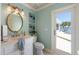 Elegant bathroom with a white vanity, gold fixtures, and view to the waterfront through the outdoor patio at 336 S Orchid Dr, Ellenton, FL 34222