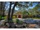 Clubhouse exterior with verdant landscaping, a red door, and ample parking spaces at 3461 Tallywood Cir # 7067, Sarasota, FL 34237