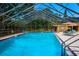 A community pool in a screened enclosure with lounge chairs and an umbrella-covered table at 3461 Tallywood Cir # 7067, Sarasota, FL 34237