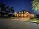 Elegant home at night featuring a brick driveway, attached garage, and manicured landscaping at 3712 59Th Avenue E Cir, Ellenton, FL 34222