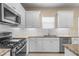 Modern kitchen featuring stainless steel appliances, white cabinets, and granite countertops at 3835 Autumn Fern Ter, Sarasota, FL 34243