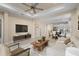 Bright living room featuring modern furniture, a ceiling fan, and an open floor plan leading into the kitchen and dining area at 3835 Autumn Fern Ter, Sarasota, FL 34243