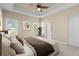 Inviting primary bedroom with a tray ceiling, a ceiling fan, and windows with a view of the outdoors at 3835 Autumn Fern Ter, Sarasota, FL 34243