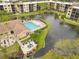 An aerial view shows a community pool, clubhouse, and a scenic pond with fountains, surrounded by lush greenery at 515 30Th Ave W # H410, Bradenton, FL 34205